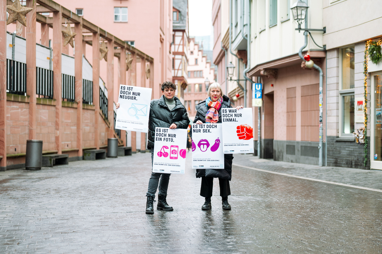 Zwei Personen halten vier Plakate der Initiative in die Höhe. Im Hintergrund ist der Frankfurter Römer sichtbar